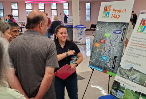 River Authority Employee explains Westside Creeks project to people around a table.